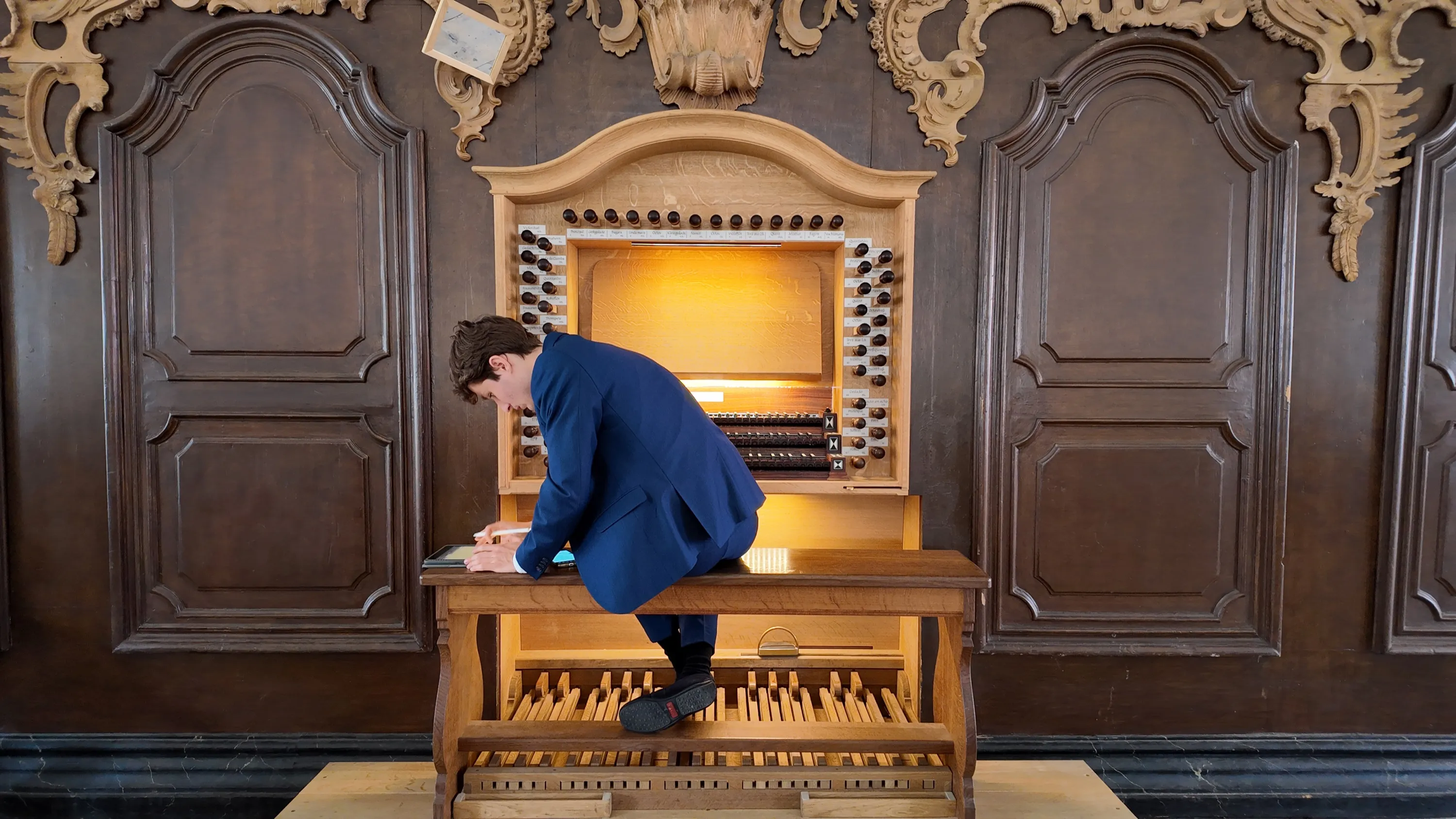 Lukas Höver am Spieltisch einer barocken Orgel, über die Noten gebeugt