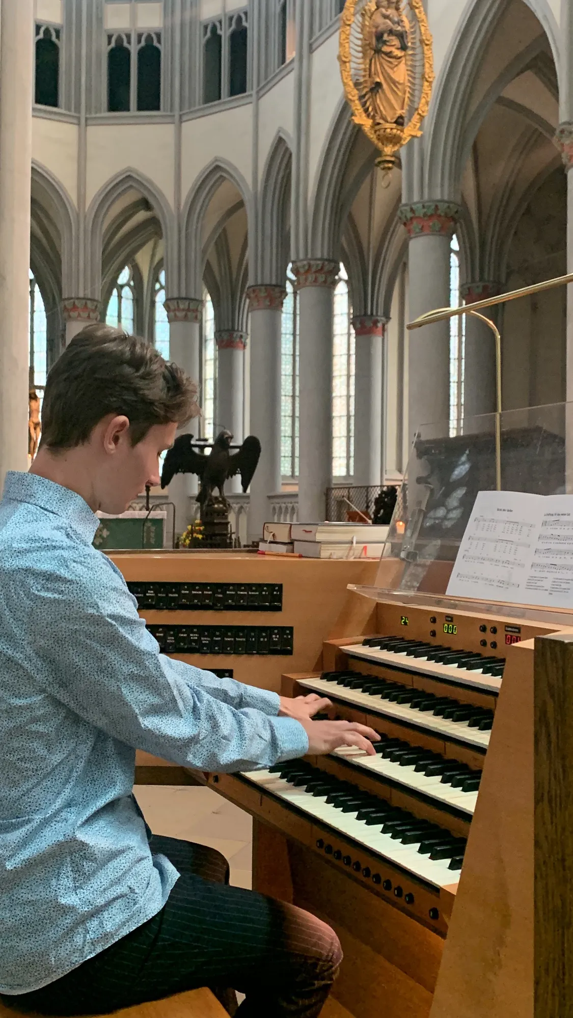 Lukas Höver am Spieltisch einer Orgel im Chorraum einer gotischen Kirche